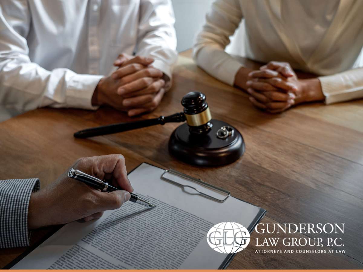 Lawyer reviewing documents with a couple at a desk, discussing legal matters related to a noncitizen spouse at Gunderson Law Group