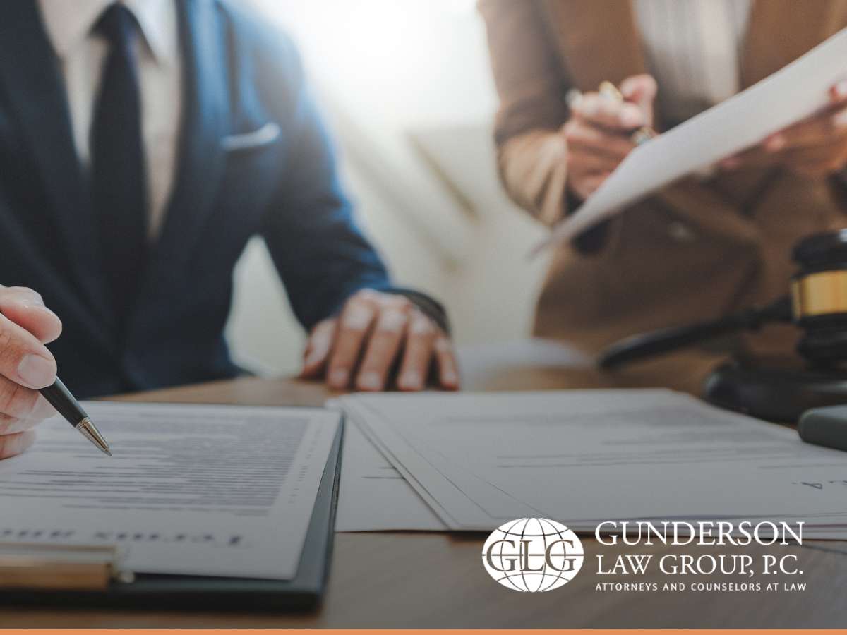 Lawyers discussing documents at a desk with Gunderson Law Group logo, focusing on estate planning