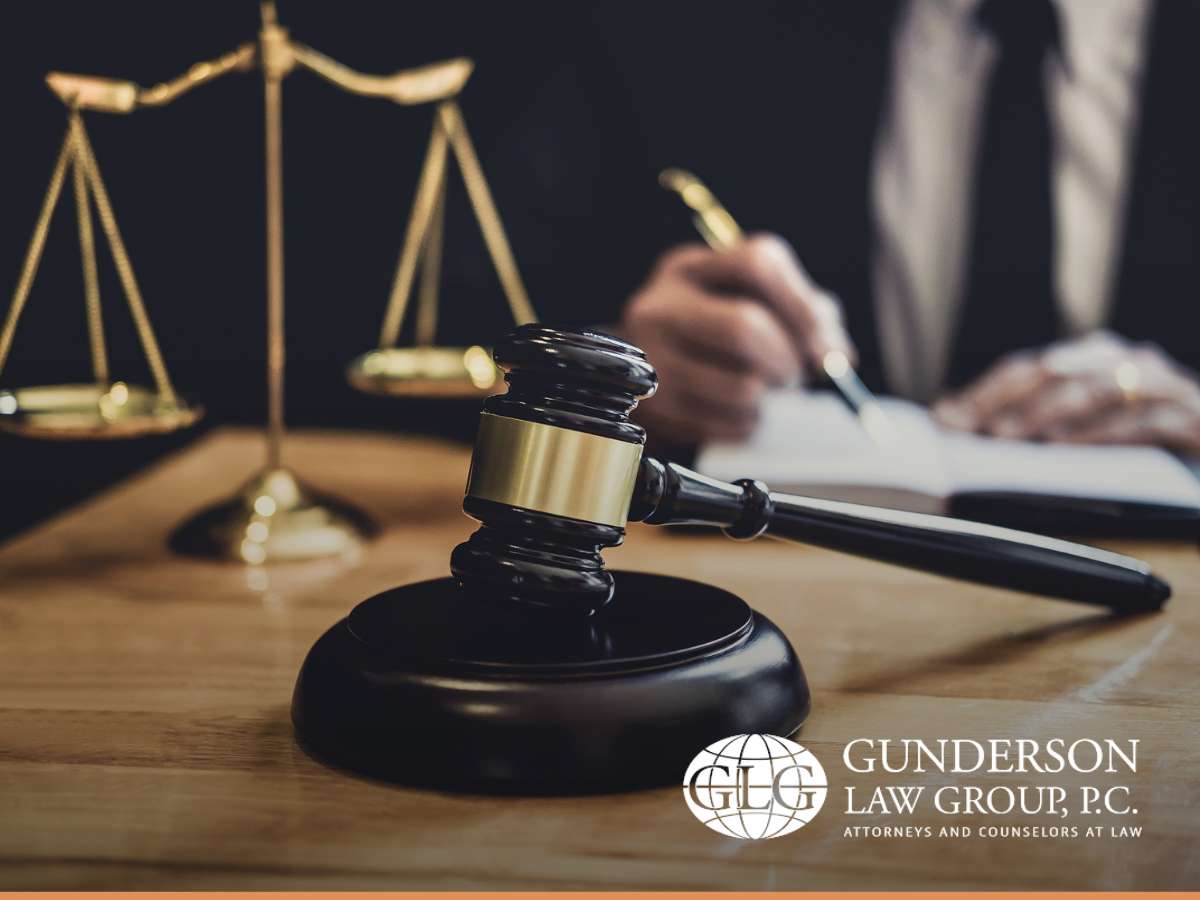 Tilted scales, gavel, and attorney drafting an estate plan at Gunderson Law Group